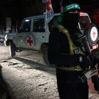 Iillustration : Un terroriste du Hamas montant la garde alors qu'un véhicule de la Croix-Rouge transporte des otages qui viennent d'être libérés des geôles du Hamas, à Rafah, dans le sud de la bande de Gaza, le 28 novembre 2023. (Crédit : AFP)