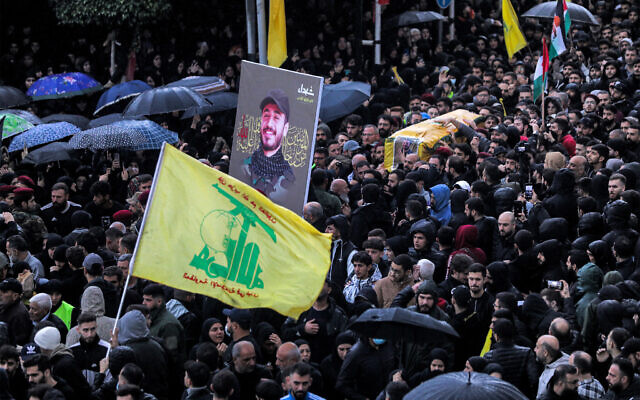 Une foule en deuil marchant avec les corps de trois terroristes du Hezbollah tués dans le sud-ouest de la Syrie, le long du plateau du Golan, lors des funérailles dans la banlieue sud de Beyrouth, le 9 décembre 2023. (Crédit : Ibrahim Amro/AFP)