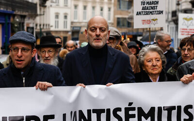 Le président de la Ligue belge contre l'antisémitisme, Joel Rubinfeld (au centre), porte une banderole alors qu'il participe à une marche contre l'antisémitisme, à Bruxelles, le 10 décembre 2023. (Crédit : Simon Wohlfahrt / AFP)