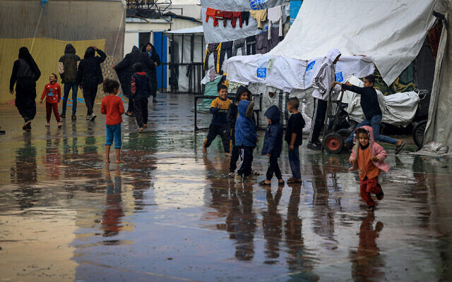 Des enfants palestiniens jouent sous la pluie à Rafah, dans le sud de la bande de Gaza, le 12 décembre 2023. (Crédit : MAHMUD HAMS / AFP)