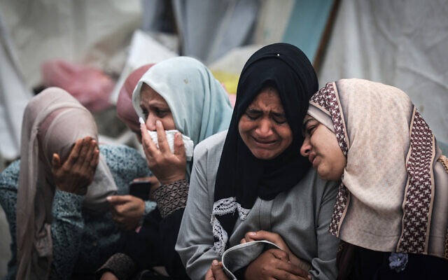Des Palestiniens pleurant la mort de leurs proches suite à une frappe israélienne sur le camp de réfugiés de Maghazi, le 25 décembre 2023. (Crédit : Mahmud Hams/AFP)