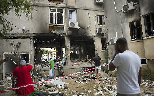 Des Israéliens inspectent un immeuble résidentiel endommagé, touché par une roquette tirée depuis la bande de Gaza, à Ashkelon, en Israël, le 9 octobre 2023. (Crédit : Erik Marmor/AP)