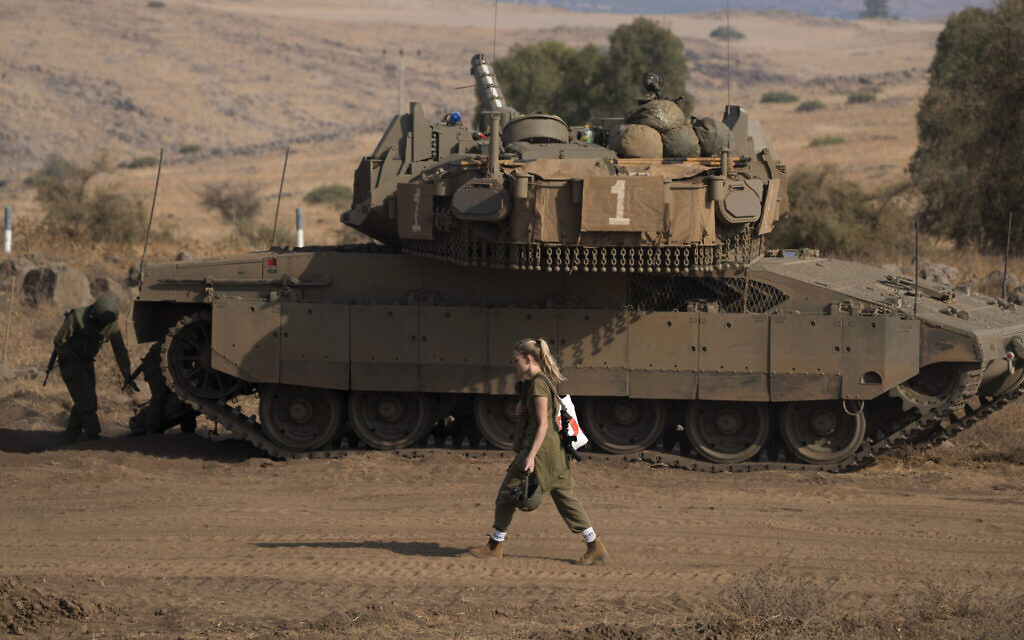 Une soldate israélienne devant un char près de la frontière avec le Liban, le 14 octobre 2023. (Crédit : AP Photo/Petros Giannakouris)