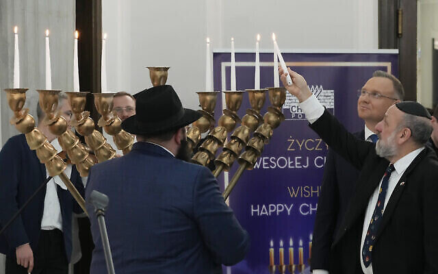 Des députés, le président Andrzej Duda, deuxième à droite, et des membres de la communauté juive polonaise pour l'allumage des bougies lors de la dernière nuit de Hanoukka au parlement de Varsovie, en Pologne, le jeudi 14 décembre 2023. (Crédit : AP/Czarek Sokolowski)
