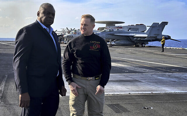 Le secrétaire américain à la Défense Lloyd Austin, à gauche, s'entretenant avec le commandant de l'USS Gerald R. Ford, le capitaine de vaisseau Rick Burgess, lors d'une visite inopinée du navire, le 20 décembre 2023. (Crédit : Tara Copp/AP Photo)
