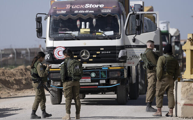 Des soldats israéliens inspectant un camion égyptien transportant de l'aide humanitaire pour la bande de Gaza, au point de passage de Kerem Shalom, dans le sud d'Israël, le 22 décembre 2023. (Crédit : Maya Alleruzzo/AP Photo)