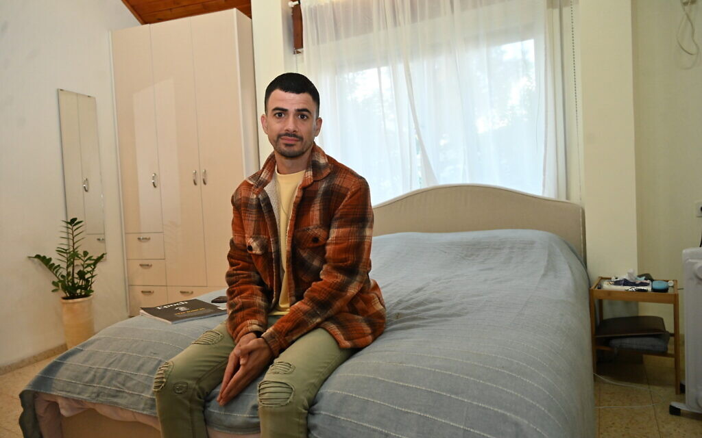 Nadav Tzabari sur son lit, dans son logement temporaire du kibboutz Mishmar HaEmek, le 6 décembre 2023. (Crédit : Canaan Lidor/Times of Israel)