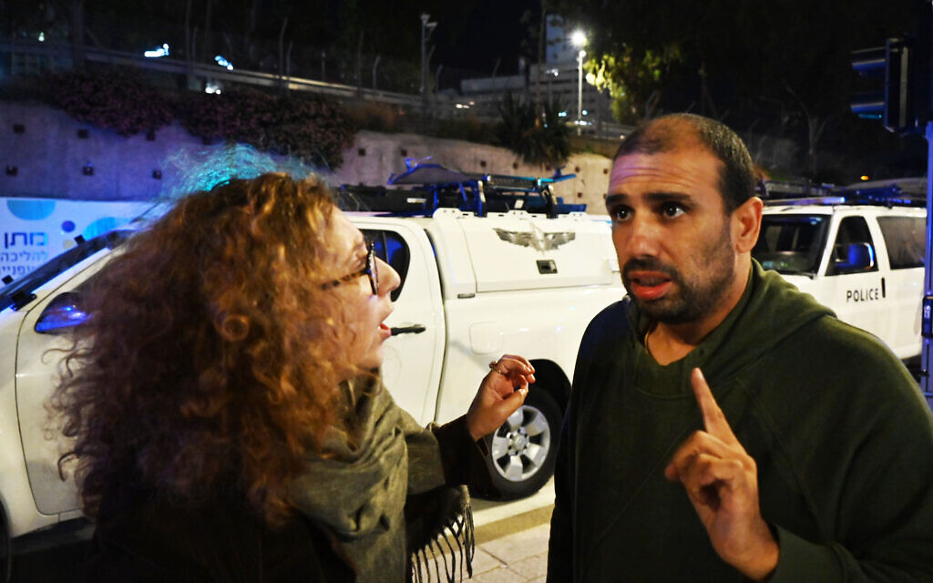 Eyal Lahiani, à droite, parle lors d'un rassemblement à Tel Aviv avec une manifestante, qui contrairement à lui favorable à la conclusion d'un accord avec le Hamas portant sur un échange de prisonniers, le 16 décembre 2023.  (Crédit : Canaan Lidor/Times of Israel)