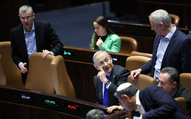 Le Premier ministre Benjamin Netanyahu, au centre, parlant avec le ministre du cabinet de guerre Benny Gantz lors d'une discussion et d'un vote sur la mise à jour du budget de l'État au plénum de la Knesset, à Jérusalem, le 14 décembre 2023. (Crédit : Yonatan Sindel/Flash90)