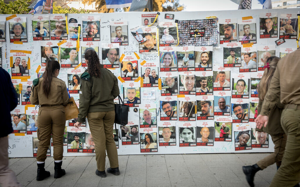 Des gens passant devant des photos de civils pris en otage par des terroristes du Hamas à Gaza, sur la "Place des Otages", à Tel Aviv, le 19 décembre 2023. (Crédit : Miriam Alster/FLASH90)