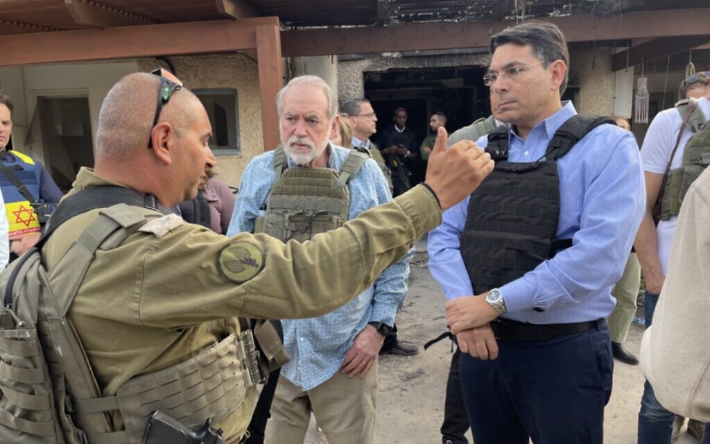 Mike Huckabee, au centre, se tenant aux côtés de l'ancien envoyé israélien à l'ONU Danny Danon, à Kfar Aza, le 20 décembre 2023. (Crédit : Sam Sokol)