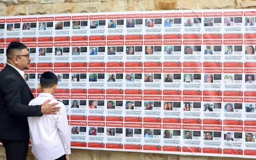 Le rabbin Yaakov Baruch regardant des affiches avec les noms et les photos d’Israéliens pris en otage par le Hamas. (Crédit : Yaakov Baruch via JTA)