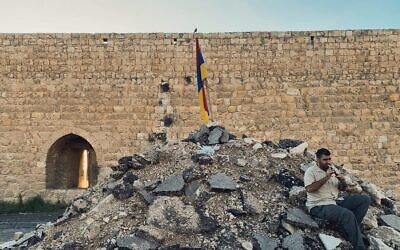 Joe Zaarour, membre de la communauté arménienne, joue de la flûte sur un monticule de débris après la destruction, par des bulldozers, d'une partie du Jardin des vaches dans le quartier arménien de Jérusalem, dans la Ville Ville, le 24 novembre 2023. (Crédit : Sarah Tuttle Singer/Times of Israel)