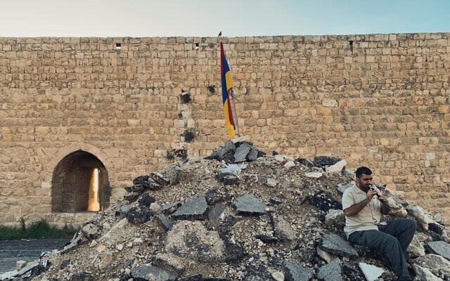 Joe Zaarour, membre de la communauté arménienne, joue de la flûte sur un monticule de débris après la destruction, par des bulldozers, d'une partie du Jardin des vaches dans le quartier arménien de Jérusalem, dans la Ville Ville, le 24 novembre 2023. (Crédit : Sarah Tuttle Singer/Times of Israel)