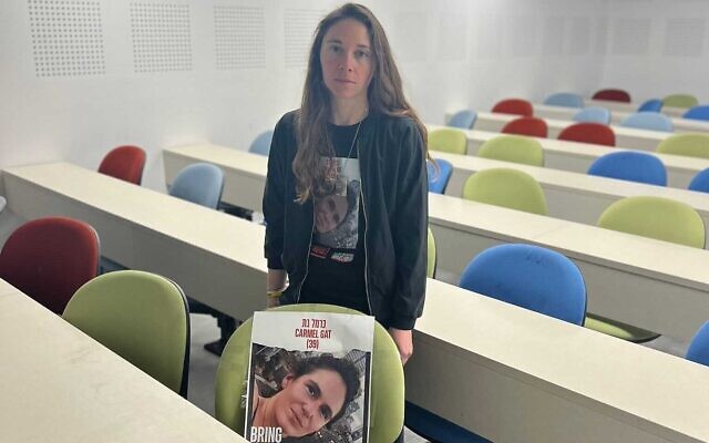 Shay Dikman accroche une affiche montrant le visage de sa cousine Carmel Gat dans toutes les salles de cours de l'Université hébraïque de Jérusalem, le 31 décembre 2023. (Crédit : Université hébraïque)