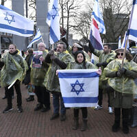 Des manifestants brandissqnt des drapeaux israéliens et néerlandais, et tenant des photos des otages enlevés lors de l'attaque transfrontalière du Hamas en Israël le 7 octobre, lors d'une manifestation devant la Cour internationale de justice, à La Haye, aux Pays-Bas, le 11 janvier 2024 (Crédit : Patrick Post/AP)