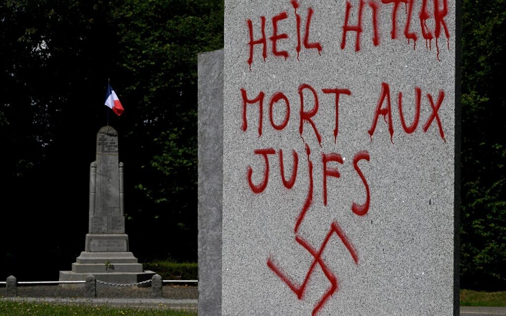 Illustration : Un graffito en allemand et en français indiquant "Salut Hitler, mort aux Juifs" et avec une croix gammée, sur un monument à la mémoire de 55 personnes exécutées à cet endroit par les nazis en 1944 pendant la Seconde Guerre mondiale, à Ploeuc-L'Hermitage, à une vingtaine de kilomètres au sud de Saint-Brieuc, dans l'ouest de la France, le 17 juillet 2023. (Crédit : Damien Meyer/AFP)