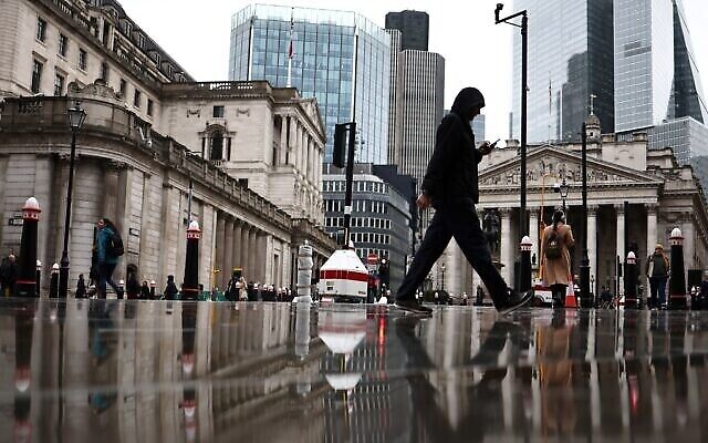 Des personnes passent devant le bâtiment de la Banque d'Angleterre (à gauche) et le bâtiment de la Bourse (à droite), dans le quartier financier au centre de Londres, le 2 novembre 2023. (Crédit : HENRY NICHOLLS / AFP)