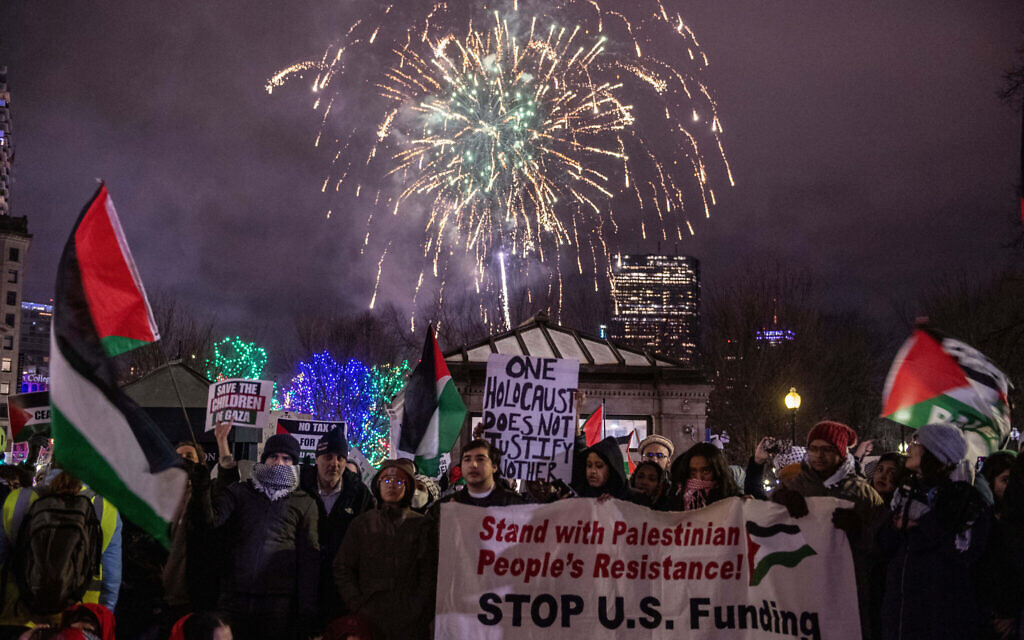 Des feux d'artifice de la Saint-Sylvestre sont tirés dans le ciel alors que des manifestants protestent contre Israël dans le cadre de la guerre contre le Hamas à Gaza, à Boston, dans le Massachusetts, le 31 décembre 2023. (Crédit : Joseph Prezioso/AFP)