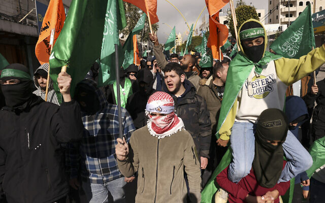 De jeunes Palestiniens brandissent à Hébron, en Cisjordanie, les drapeaux verts du groupe terroriste palestinien du Hamas lors d'une manifestation suite à l'assassinat du numéro 2 du Hamas, Saleh al-Aruri, au Liban, le 3 janvier 2024. (Crédit : HAZEM BADER / AFP)