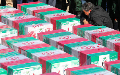 Un homme se recueillant devant des cercueils drapés du drapeau iranien des victimes tuées dans une double explosion le 3 janvier, alors qu'elles participaient à une commémoration marquant l'anniversaire de l'assassinat du général des CGRI, Qassem Soleimani, dans la ville de Kerman, au sud de l'Iran, le 5 janvier 2024. (Crédit : Présidence iranienne/AFP)