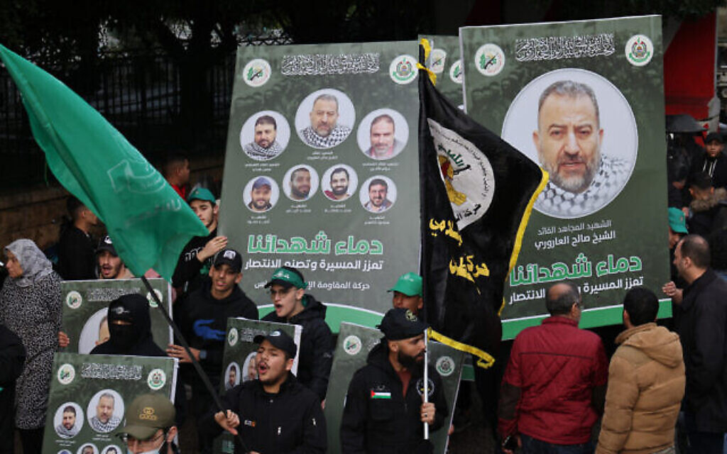 Des gens brandissent des portraits du haut responsable du Hamas Saleh al-Arouri, tué et d'autres responsables tués le 2 janvier 2024 lors d'une frappe dans la banlieue sud de Beyrouth, lors de leur cortège funèbre dans la capitale libanaise le 4 janvier 2024. (Crédit : Anwar Amro/AFP)