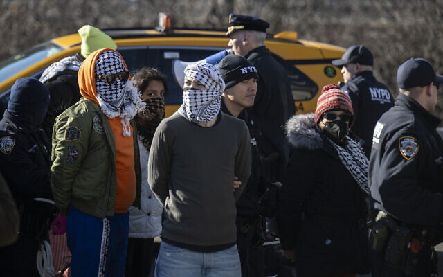 Des agents du NYPD arrêtent des manifestants pro-palestiniens alors qu'ils bloquaient l'entrée du pont de Brooklyn à Manhattan, le 8 janvier 2024, à New York. (Crédit : ANGÉLA WEISS/AFP)