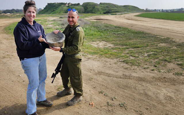 Le lieutenant-colonel Yair Amitsur et Sarah Tal, tous les deux de l'Autorité israélienne des antiquités, avec le mortier servant à broyer des céréales découvert dans une zone de transit à proximité de Gaza, une photo diffusée le 7 janvier 2024. (Crédit : Ilan Glick/IAA)