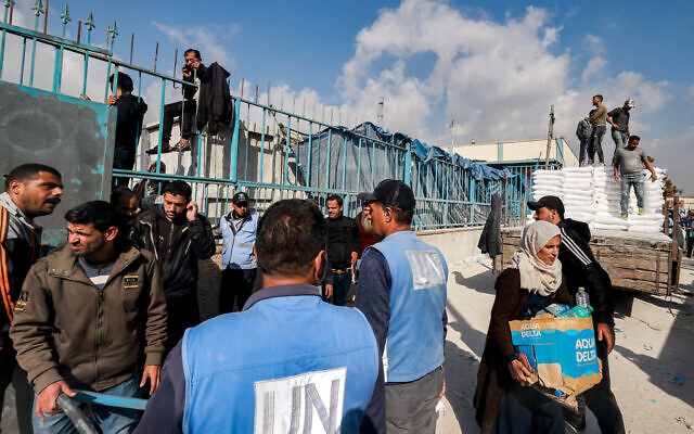 Des employés de l'agence chargée des réfugiés palestiniens à l'ONU (UNRWA) distribuant des rations de farine et autres approvisionnements aux civils dans un entrepôt de l'UNRWA, à Rafah, dans le sud de Gaza, le 12 décembre 2023. (Crédit :  Mohammed Abed/AFP)