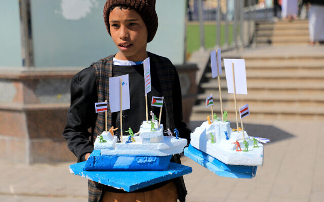 Un jeune Yéménite vend des maquettes du cargo Galaxy Leader, saisi par les combattants huthis en novembre 2023, à Sanaa le 18 janvier 2024. (Crédit :  MOHAMMED HUWAIS / AFP)