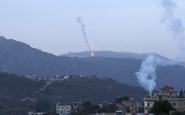 De la fumée s'échappant d'une maison touchée par des frappes aériennes israéliennes alors que des fusées éclairantes tombent sur le village de Kfar Kila, au sud du Liban, près de la frontière avec Israël, le 19 janvier 2024. (Crédit : Hasan Fneich/AFP)