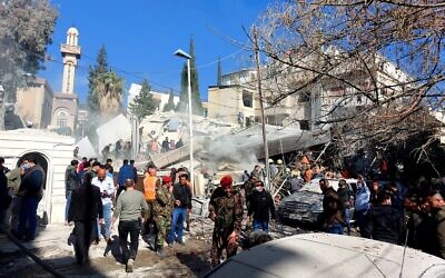 Les forces de sécurité et des badauds rassemblés devant un bâtiment détruit dans une frappe attribuée à Israël, à Damas, le 20 janvier 2024. (Crédit : AFP)