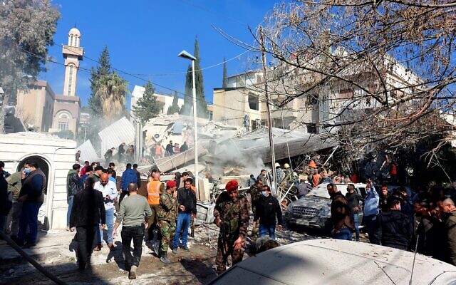 Les forces de sécurité et des badauds rassemblés devant un bâtiment détruit dans une frappe israélienne présumée à Damas, le 20 janvier 2024. (Crédit : AFP)