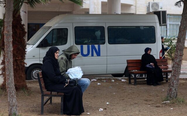 Des Palestiniens déplacés assis sur des bancs alors qu'ils attendent aux abords d'un dispensaire de l'UNRWA, agence de l'ONU chargée des réfugiés palestiniens, à Rafah, dans le sud de la bande de Gaza, le 28 janvier 2028. (Crédit :  AFP)