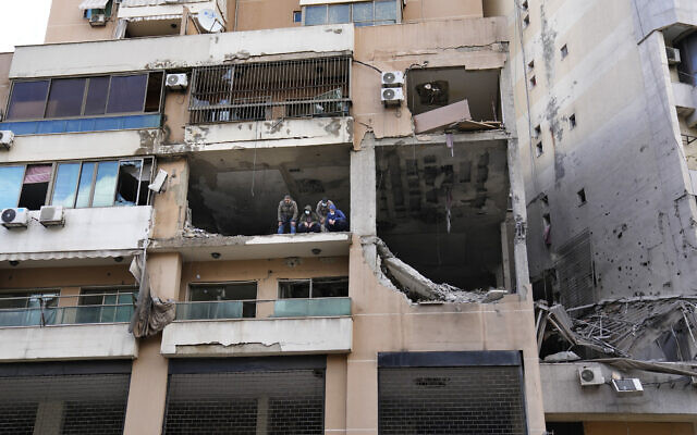 Des enquêteurs se tenant prêt dans un immeuble où une frappe imputée à Israël a tué le chef terroriste du Hamas, Saleh al-Arouri, dans la banlieue sud de Beyrouth, un bastion du Hezbollah, au Liban, le 3 janvier 2024. (Crédit : Hussein Malla/AP Photo)