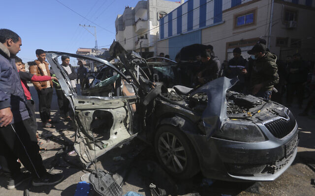 Des Palestiniens devant une voiture touchée par une frappe attribuée à Israël et dans laquelle se trouvaient deux journalistes, Hanza Dahdouh, qui travaillait pour Al-Jazeera, et un indépendant, Mustafa Thuria, qui ont été tués, le 7 janvier 2024. (Crédit : Hatem Ali/AP)