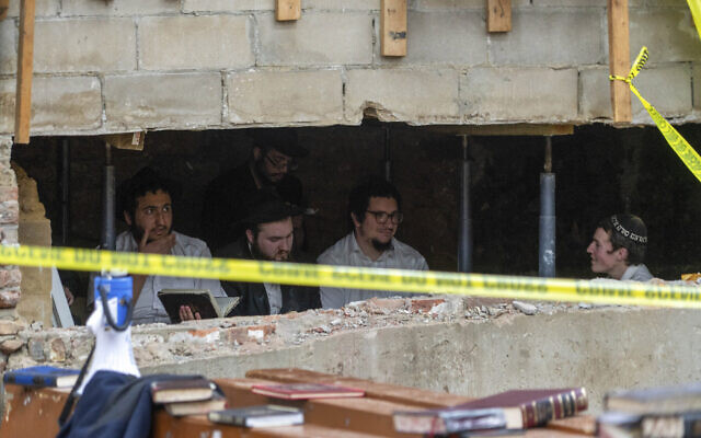 Des étudiants juifs hassidiques assis derrière une brèche dans le mur d'une synagogue qui conduit à un tunnel creusé par les étudiants au siège de Habad-Lubavitch, le 8 janvier 2024, à New York. (Crédit : Bruce Schaff via AP)