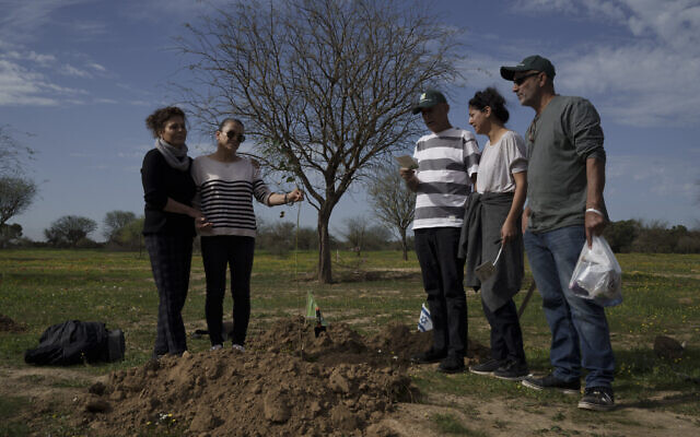 Des amis et des membres de la famille priant avant de planter un arbre à la mémoire d'une personne tuée le 7 octobre 2023 au Festival Supernova, à proximité du kibboutz Reïm, le 21 janvier 2024. (Crédit : Leo Correa/AP Photo)