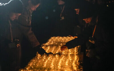 Des personnes allument des bougies près du monument du camp d'extermination nazi de Birkenau à Oswiecim, en Pologne, le samedi 27 janvier 2024. (Crédit : AP/Czarek Sokolowski)
