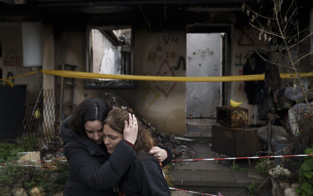 Amit Soussana, à droite, embrassée par une amie devant sa maison détruite, au kibboutz Kfar Aza, le 29 janvier 2024. (Crédit : Leo Correa/AP Photo)