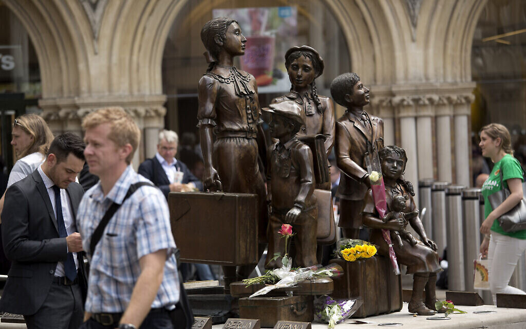 Des gerbes de fleurs ont été déposés en mémoire du Britannique Sir Nicholas Winton sur la statue commémorative « Kindertransport », oeuvre du sculpteur juif d'origine allemande Frank Meisler, devant la gare de Liverpool Street à Londres, le 2 juillet 2015. (Crédit : AP Photo/Matt Dunham)