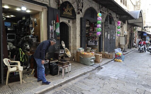 Jamal Hemmou avec des vieux tourne-disques devant sa boutique de Naplouse, en Cisjordanie, le 17 janvier 2023. (Crédit : Jaafar Ashtiyeh/AFP)