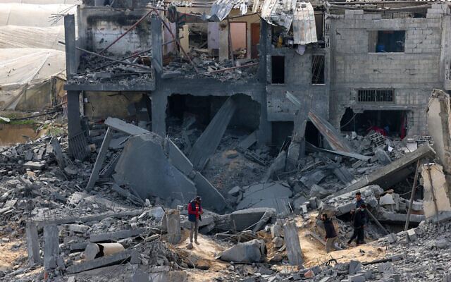 Des Palestiniens inspectent les dégâts sur un bâtiment où deux otages auraient été détenus avant d'être secourus lors d'une opération militaire de Tsahal à Rafah, dans le sud de la bande de Gaza, le 12 février 2024 (Crédit : SAID KHATIB / AFP)