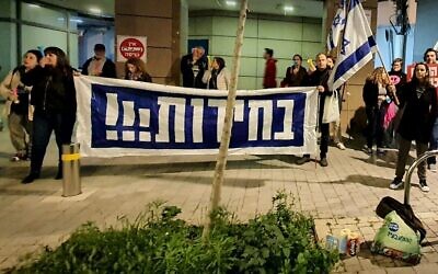 Dans une photo fournie par des militants anti-gouvernementaux, des manifestants tiennent une bannière appelant à des élections devant le domicile du ministre des Renseignements Gila Gamliel, à Tel Aviv, le 22 février 2024. (Crédit : Udi Salmanovich)