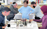 Melan Halbi, debout, regarde les autres joueurs concourir lors du tournoi de la Fédération israélienne d'échecs à Acre, au mois de janvier 2024. (Crédit : Olga Volkov)