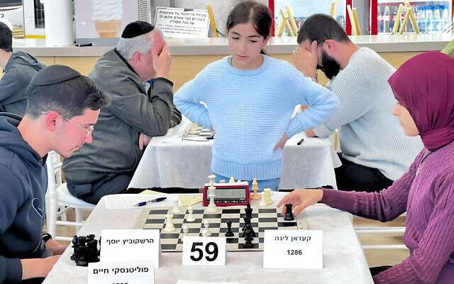 Melan Halbi, debout, regarde les autres joueurs concourir lors du tournoi de la Fédération israélienne d'échecs à Acre, au mois de janvier 2024. (Crédit : Olga Volkov)