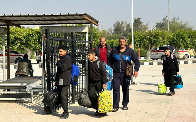 Des voyageurs quittant la bande de Gaza entrant du côté égyptien du poste-frontière de Rafah avec l'enclave palestinienne après leur évacuation, le 18 décembre 2023. (Crédit : AFP)