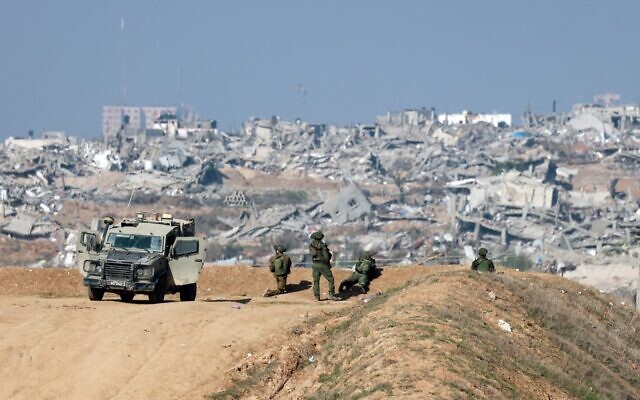 Des soldats israéliens observant Gaza City depuis la frontière israélienne avec le nord de la bande de Gaza, sur une photo prise à la frontière israélienne avec le nord de la bande de Gaza le 1er janvier 2024. (Crédit : Menahem Kahana/AFP)