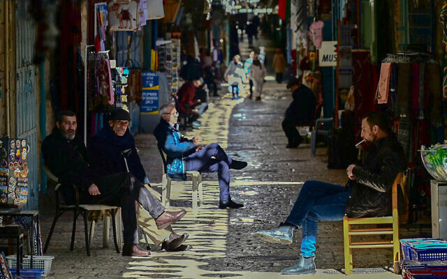 Des commerçants assis devant leurs magasins, dans la Vieille Ville de Jérusalem, le 13 janvier 2024. (Crédit : Alberto Pizzoli/AFP)