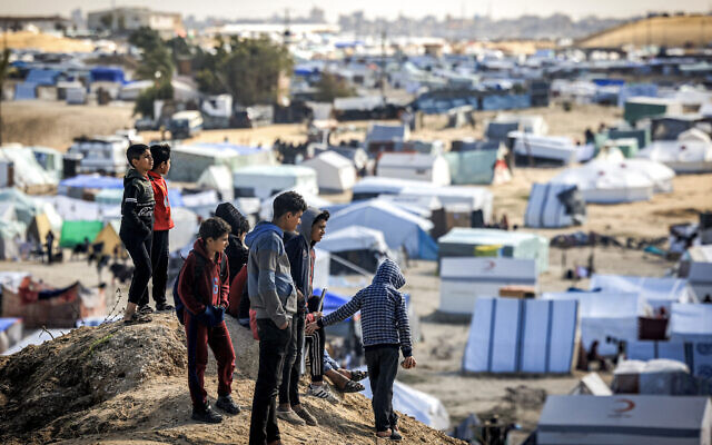 Des enfants au sommet d'une petite colline près de tentes dans un abri de fortune pour les Palestiniens qui ont fui dans le cadre du conflit actuel entre Israël et le Hamas à Rafah, dans le sud de la bande de Gaza, le 30 janvier 2024. (Crédit : Mahmud Hams/AFP)